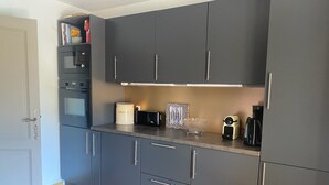 Eine moderne Küche mit grauen Schränken, einem Einbauofen, einem Toaster und einer Brotdose.