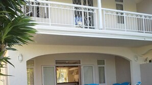 A two-story house with a balcony, a covered patio with chairs, and a stone pathway leading to the entrance. - Charming 3 bedroom villa with pool, only 4 minutes walk to amazing beach (Mont Choisy)