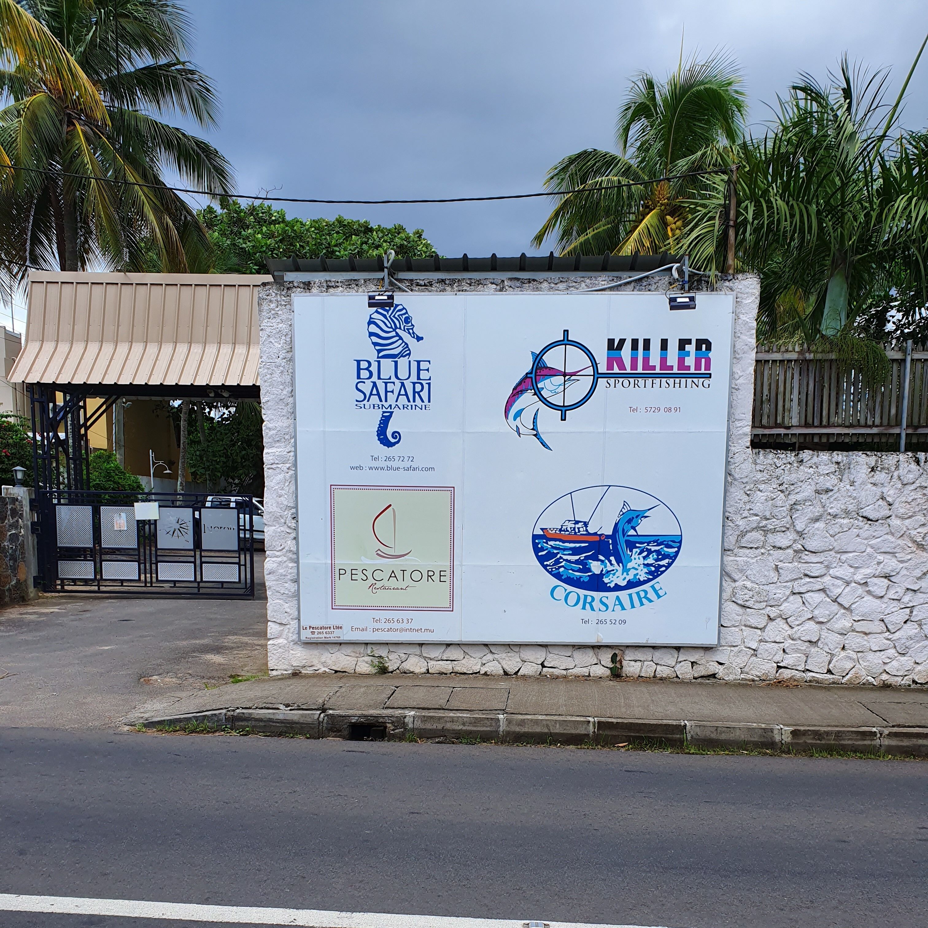 Une enseigne portant les logos de Blue Safari Submarine, Killer Sportfishing, du restaurant Pescatore et de Corsaire.