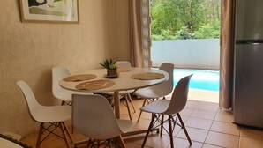 A dining area with a round table, white chairs, and a small plant. - Charming 3 bedroom villa with pool, only 4 minutes walk to amazing beach (Mont Choisy)