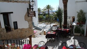 An outdoor dining area with tables and chairs, a stone wall, and a sign for 'Tasca Moralra'. - Villa Ra - Enchanting Moraira Villa with Secluded Pool and Sea View      (Alicante)