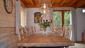 A wooden dining table with chairs, a vase with flowers, and a clock on the wall. - Luxury chalet SKI-IN / SKI-OUT. Free wifi, sauna and beautiful view !!! (Oz)