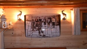 A wooden cabin interior with a wall-mounted photo collage, a wooden ceiling, and a small table with a radio. - Luxury chalet SKI-IN / SKI-OUT. Free wifi, sauna and beautiful view !!! (Oz)