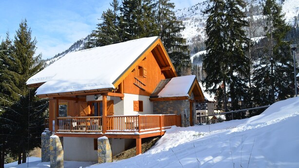 A wooden chalet with a balcony, surrounded by snow-covered trees and mountains. - Luxury chalet SKI-IN / SKI-OUT. Free wifi, sauna and beautiful view !!! (Oz)