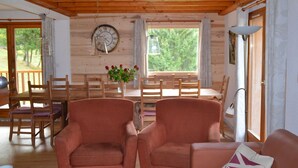 A cozy cabin interior with wooden walls, a dining area with a table and chairs, and a seating area with two armchairs. - Luxury chalet SKI-IN / SKI-OUT. Free wifi, sauna and beautiful view !!! (Oz)
