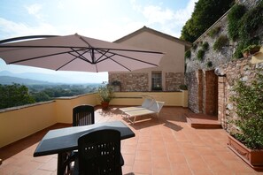 A terrace with a table and chairs, a large umbrella, and a view of the landscape. - House with character (Spello)
