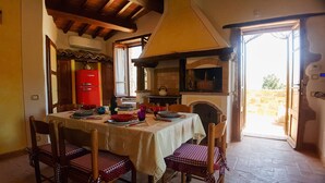 A dining area with a table set for four, surrounded by wooden chairs. A red vintage refrigerator is visible in the background.