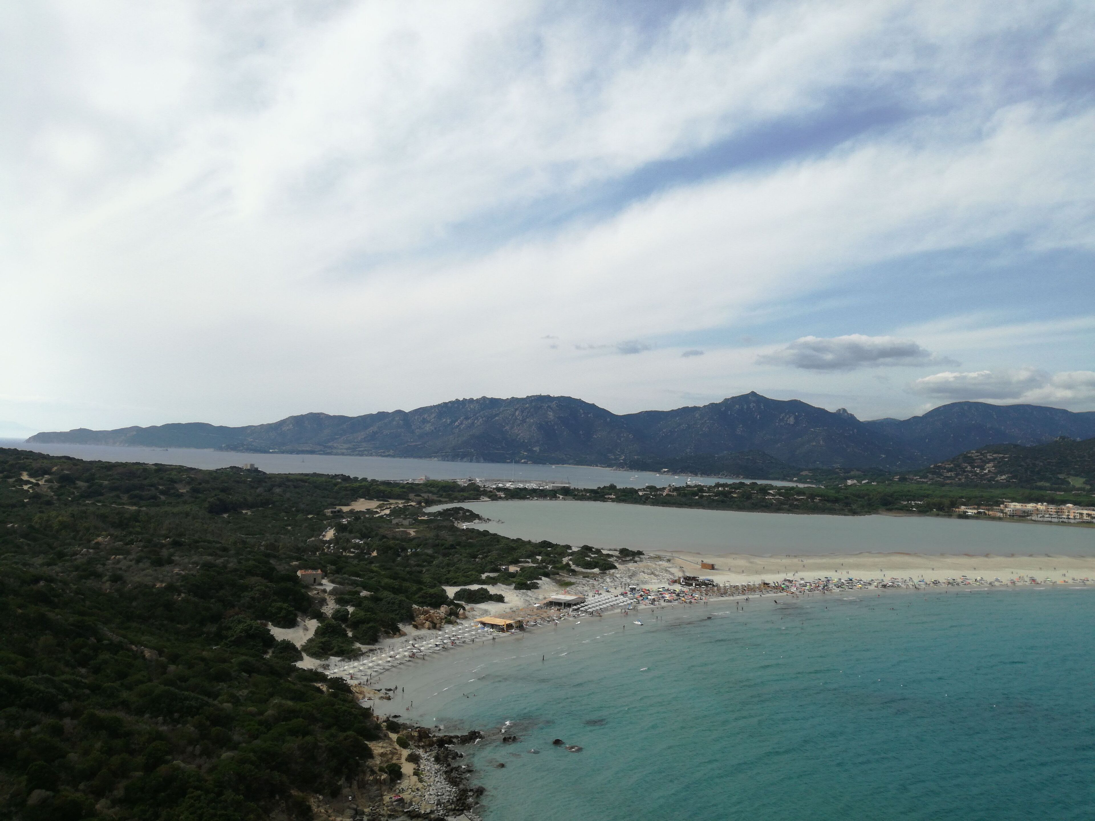 A coastal landscape with a beach, mountains, and a clear sky.
