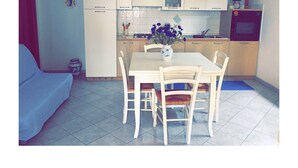 Une cuisine compacte avec des meubles blancs, une table à manger avec des chaises et un petit four.