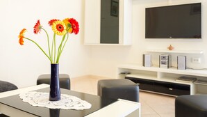A modern living room with a black table, a vase of flowers, a flat-screen TV, and a white entertainment unit. - Vacation that you'll remember for a long time :) (Korcula)