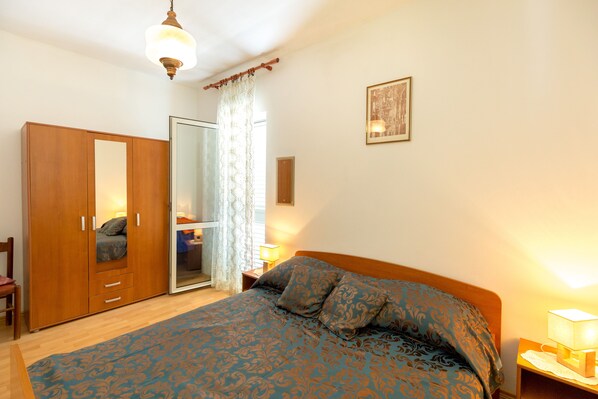 Une chambre à coucher comprenant un lit, une armoire, un miroir, une table de chevet et une lampe.