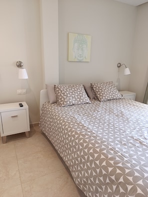 A bedroom with a bed, two nightstands, a wall-mounted lamp, and a wall decoration. - ocean view residence (Caleta De Fuste)