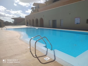 A swimming pool with a metal ladder and a tiled deck. - ocean view residence (Caleta De Fuste)