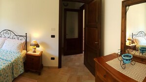 Una camera da letto con un letto, comodini, un tavolino, una cassettiera, uno specchio e una finestra.