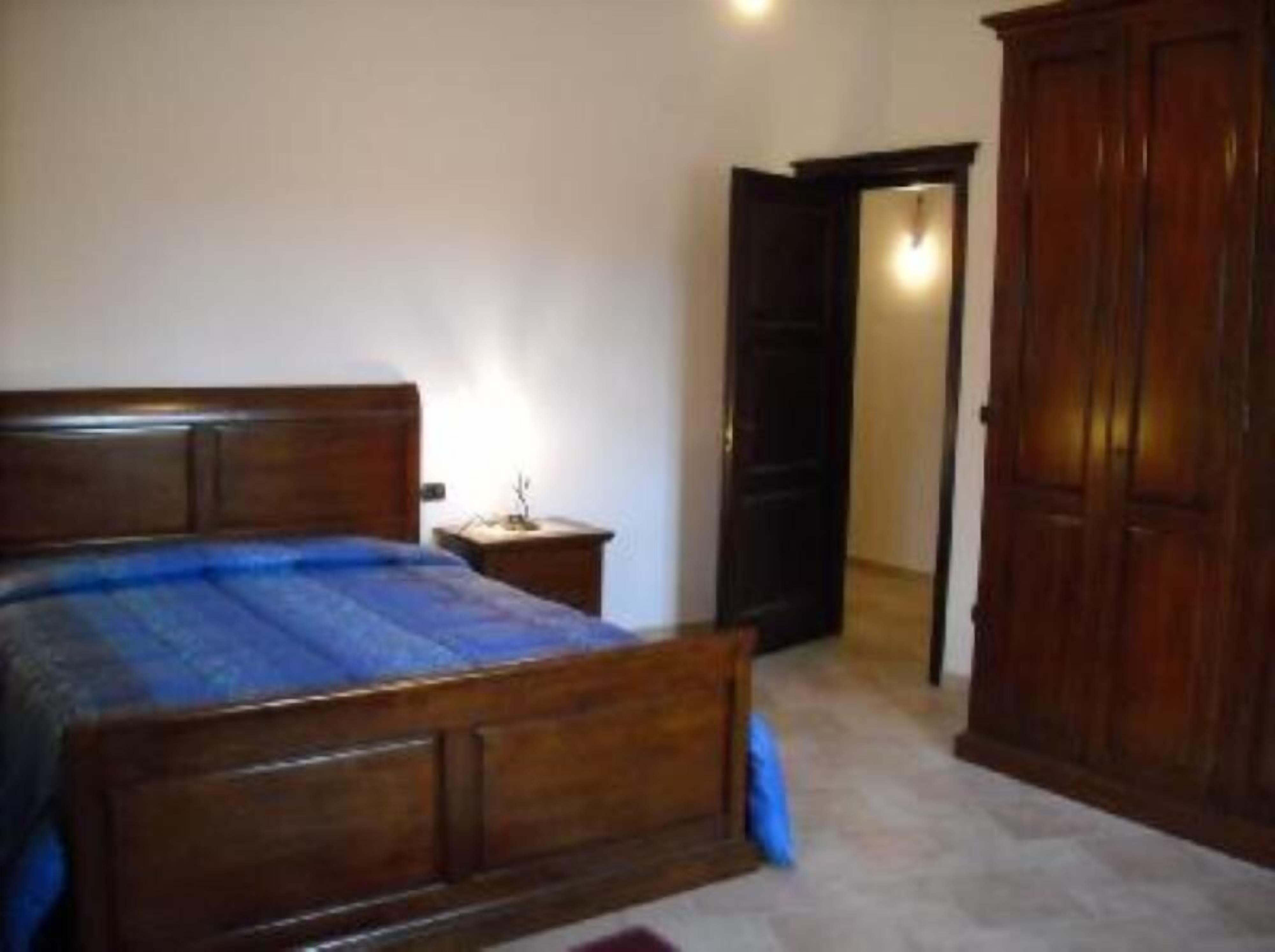 A bedroom with a wooden bed, a nightstand, and a wardrobe.
