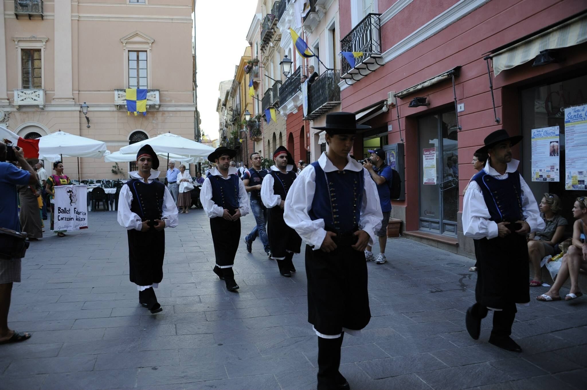 Un grupo de personas vestidas con atuendo tradicional caminan por una calle.
