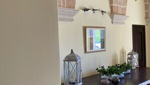 Un couloir avec une longue table en bois, des lanternes décoratives et un miroir encadré.