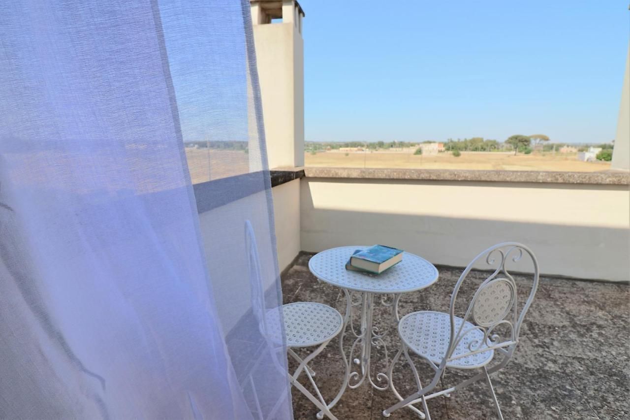 A balcony with a table and chairs, a book on the table, and a view of the landscape.