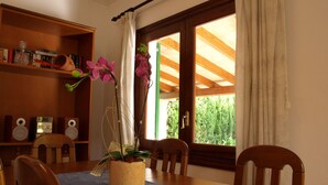 A dining area with a wooden table, chairs, a blue table runner, a potted orchid, and speakers on a shelf. - CAN LA (Wi-Fi Villa) (Pollensa)