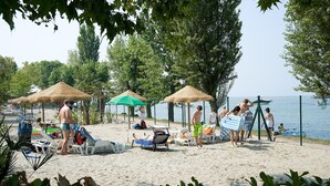 Una playa con tumbonas, sombrillas y un área delimitada por una valla.