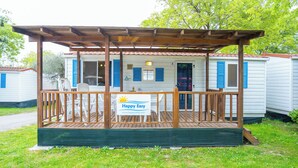 Una casa móvil con terraza de madera y un letrero que dice 'Happy Easy'.