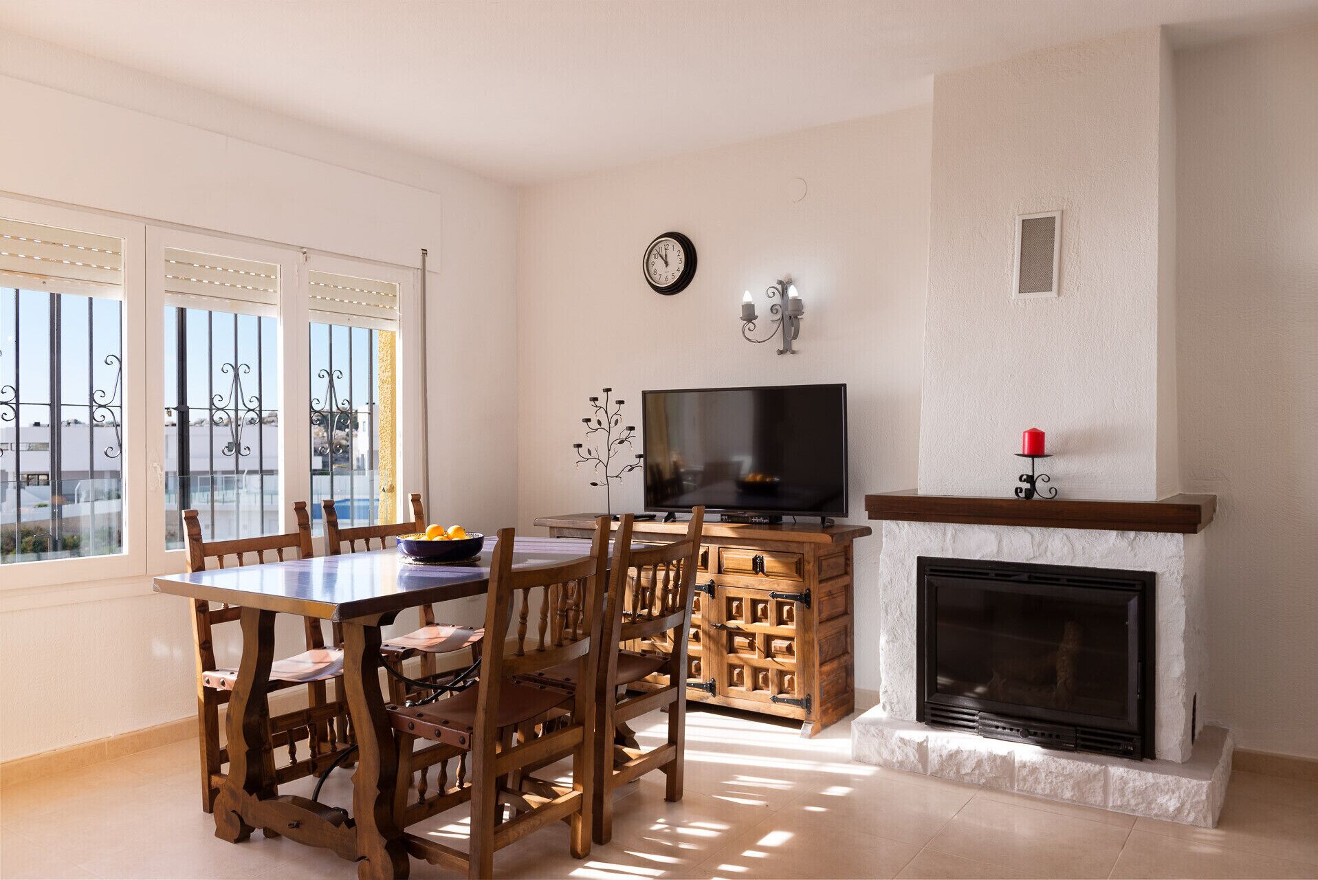 Un coin repas avec une table et des chaises en bois, un téléviseur et une cheminée.