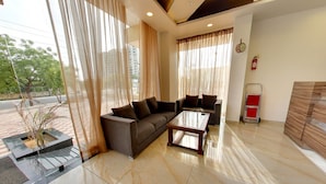 A modern living room with a sofa, coffee table, and curtains. - Hotel RG Inn (Jaipur)