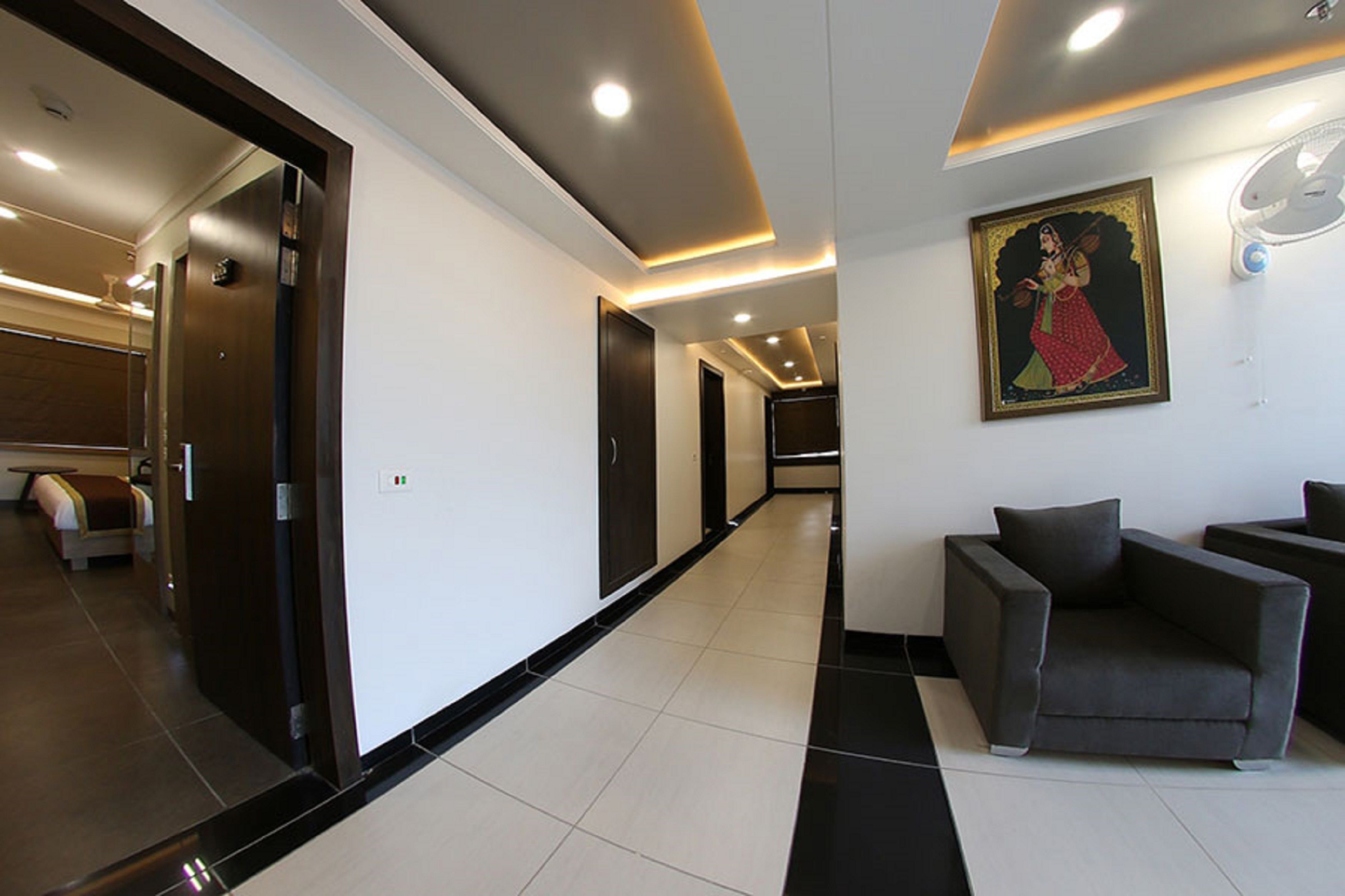 Un moderno vestíbulo de hotel con un largo pasillo, una zona de recepción con sofás y un cuadro en la pared.