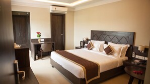 A hotel room with a large bed, a desk, a chair, and a wardrobe. - Hotel RG Inn (Jaipur)