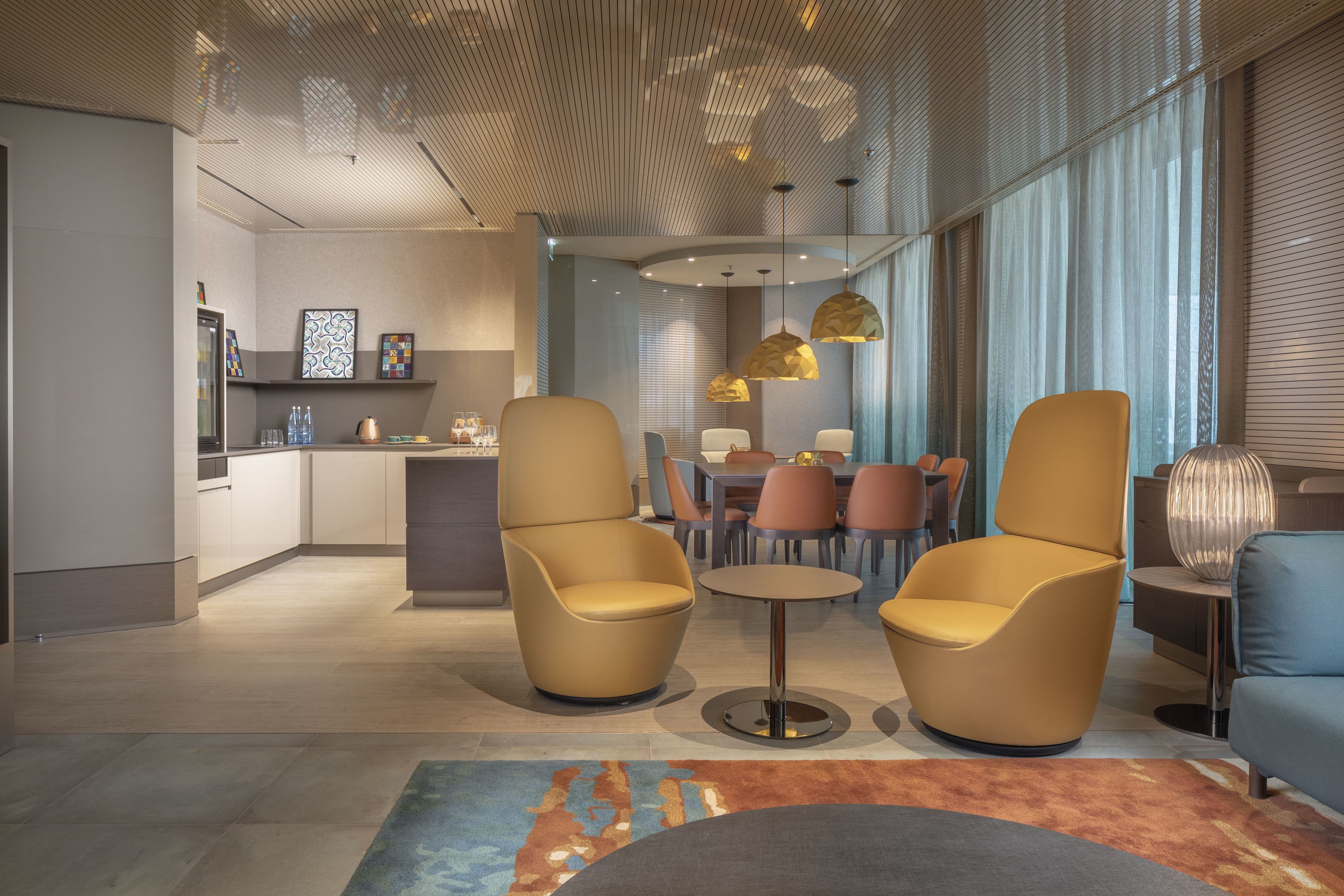 Un interior moderno con dos sillones, una mesa redonda y una zona de comedor con sillas.