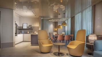 Un interior moderno con dos sillones, una mesa redonda y una zona de comedor con sillas.