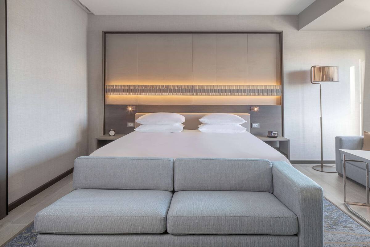 Une chambre d’hôtel moderne dotée d’un grand lit, d’un coin salon et d’un bureau.