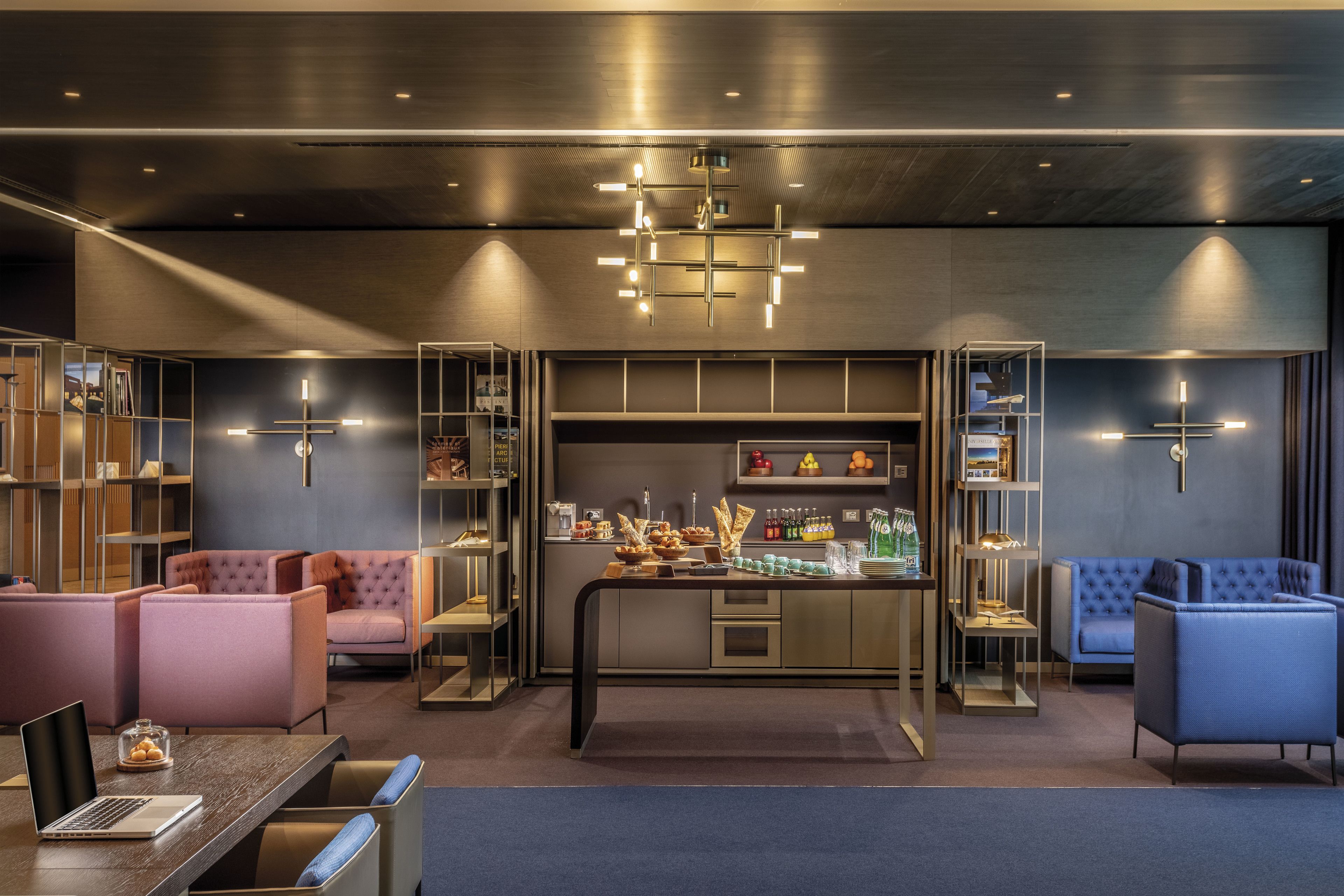 Un moderno vestíbulo de hotel con una recepción central, zonas de estar y estanterías integradas con servicios.