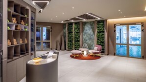 Un espace d’accueil moderne comprenant un comptoir de réception, un coin salon et de grandes fenêtres offrant une vue dégagée.