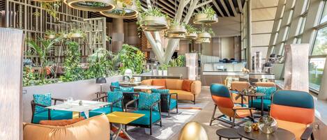 A modern interior with seating areas, tables, and hanging planters.