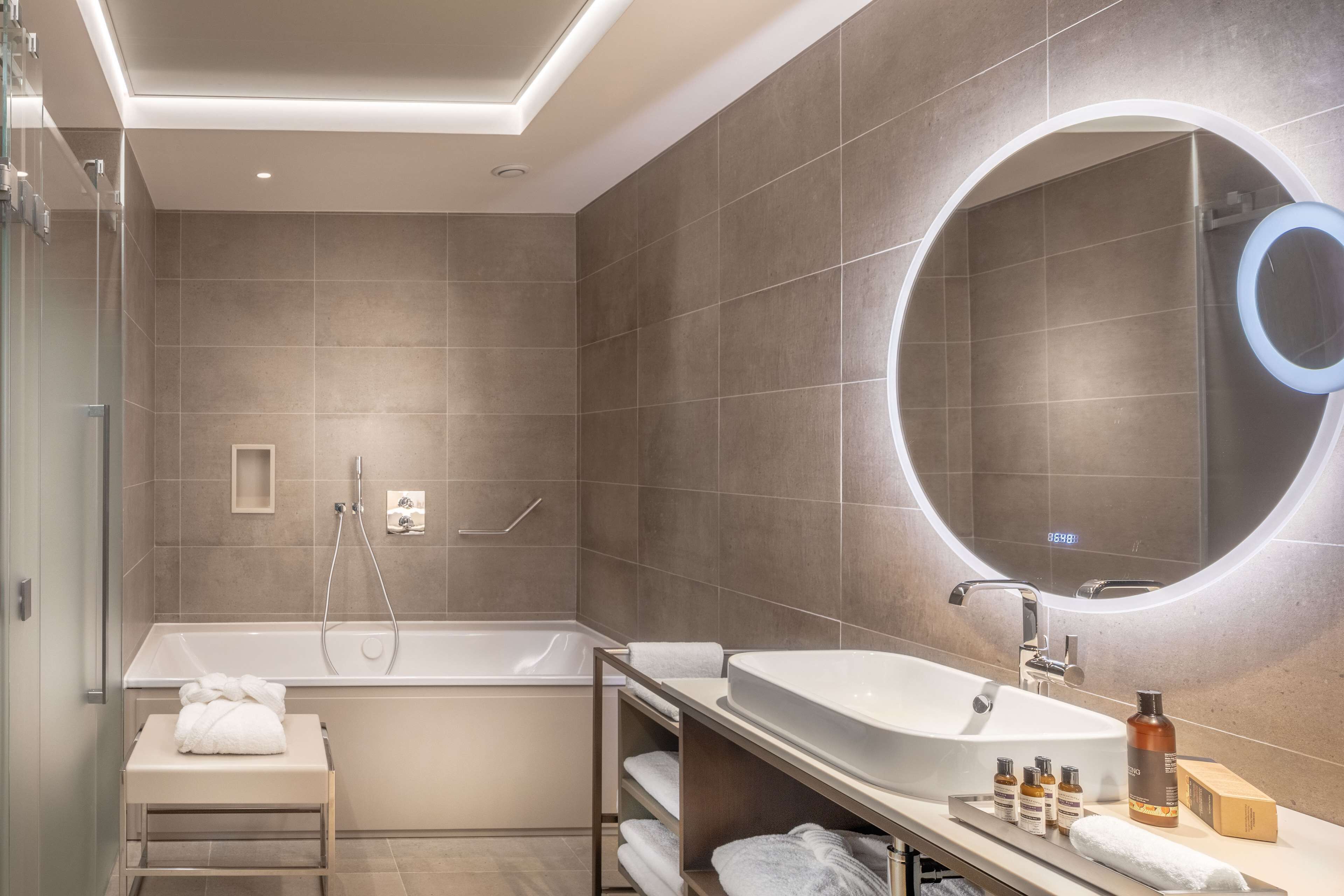 A modern bathroom with a freestanding bathtub, a vanity with a large mirror, and neatly arranged towels.