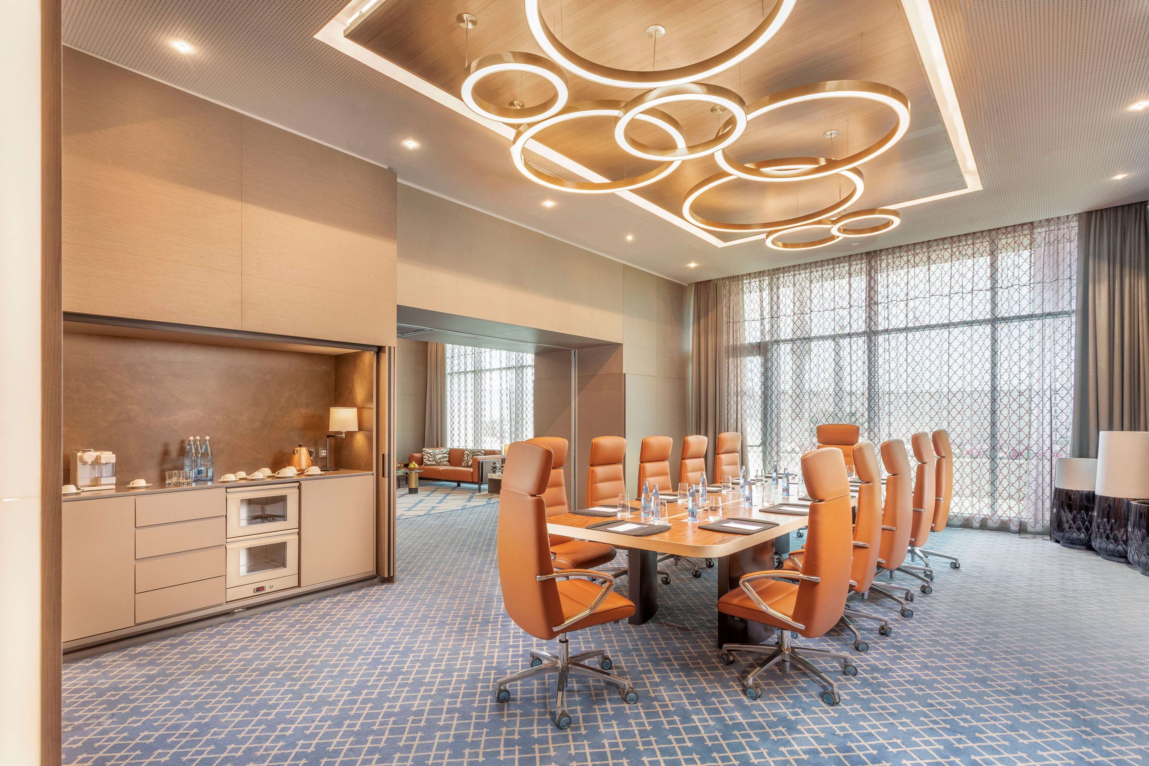 A conference room with a long table, multiple chairs, and a modern ceiling design.