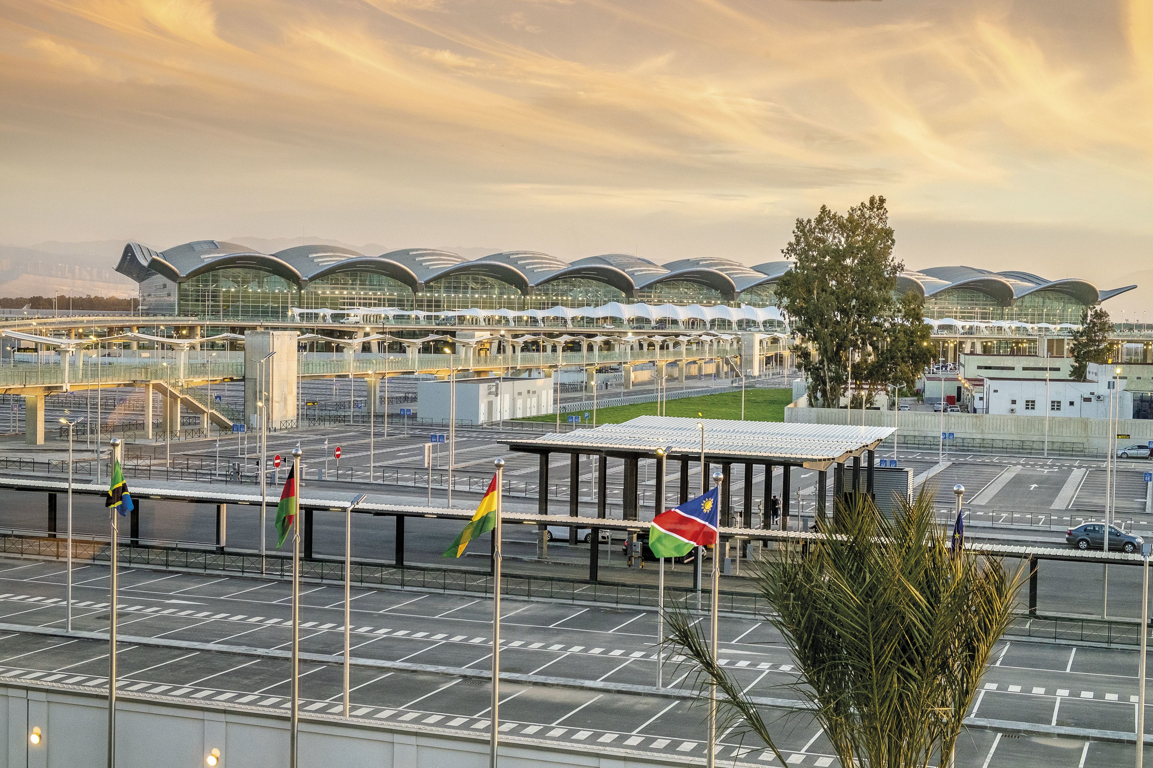 Una terminal aeroportuaria moderna con varias cubiertas curvas y un pasillo cubierto.