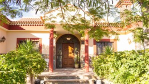 A traditional building with a tiled roof, a central entrance with a wooden door, and a stone staircase leading up to it.