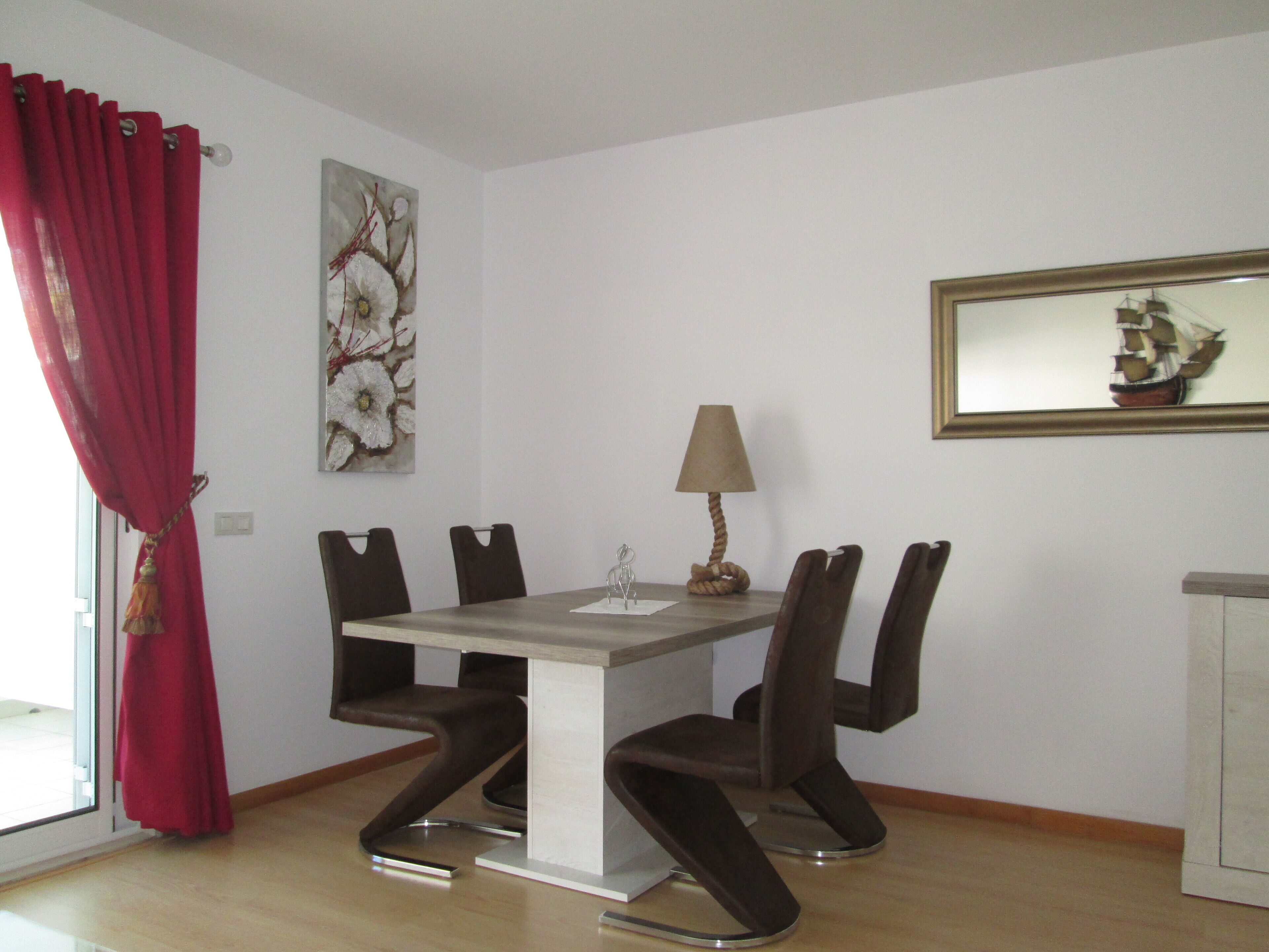 A dining area with a table, chairs, a lamp, and artwork on the walls.