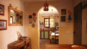 A cozy kitchen with wooden cabinets, a dining table, and a hanging light fixture.
