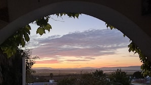 A balcony with a view of a sunset over a landscape.