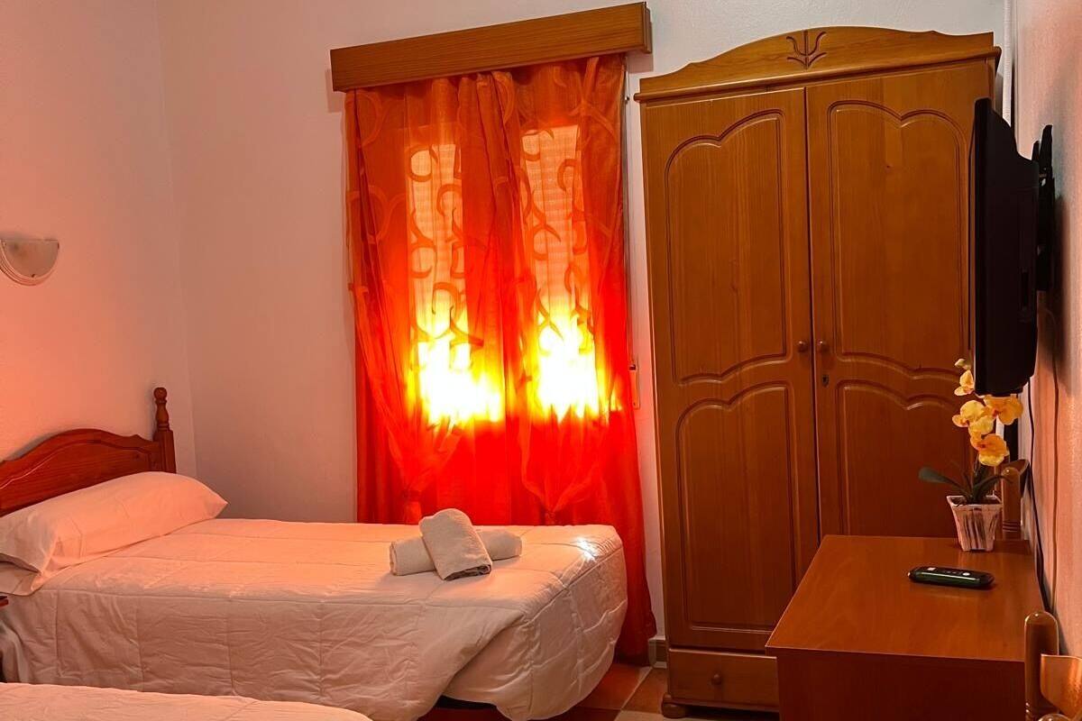 Une chambre d’hôtel avec deux lits, une armoire en bois, un bureau et un téléviseur.
