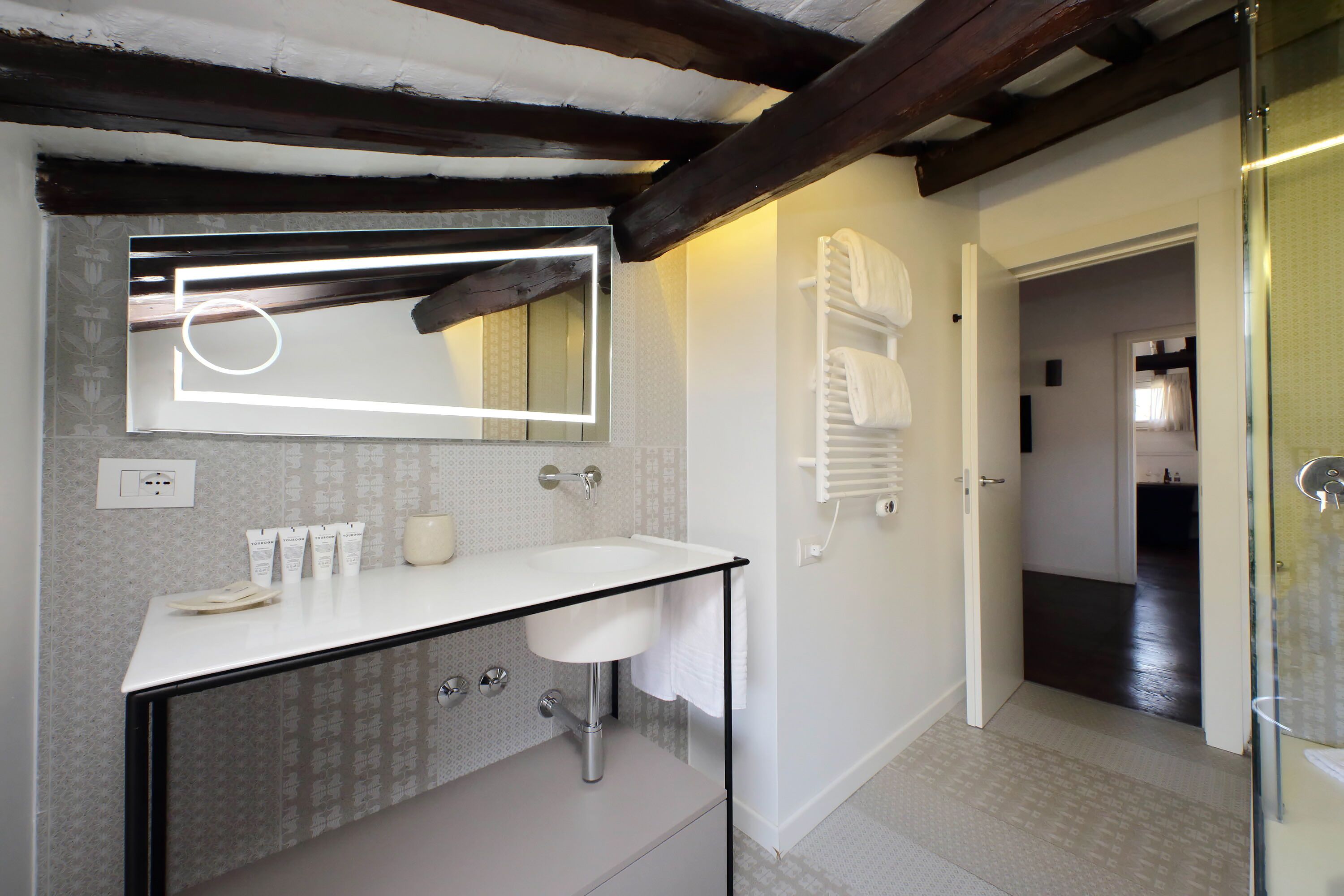 Un bagno moderno con lavandino, specchio e portasciuga bianchi.