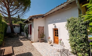 A white building with a tiled patio, a wooden door, and potted plants. - Charming cottage with large pool, garden & views of Pyrénées, near Carcassonne (Montazels)