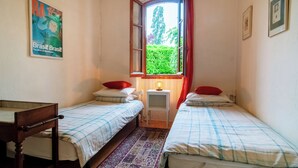 A room with two single beds, a small table, a window with curtains, and a poster on the wall. - Charming cottage with large pool, garden & views of Pyrénées, near Carcassonne (Montazels)