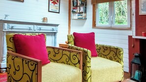 A room with a skylight, a fireplace, and two armchairs with red cushions. - Charming cottage with large pool, garden & views of Pyrénées, near Carcassonne (Montazels)