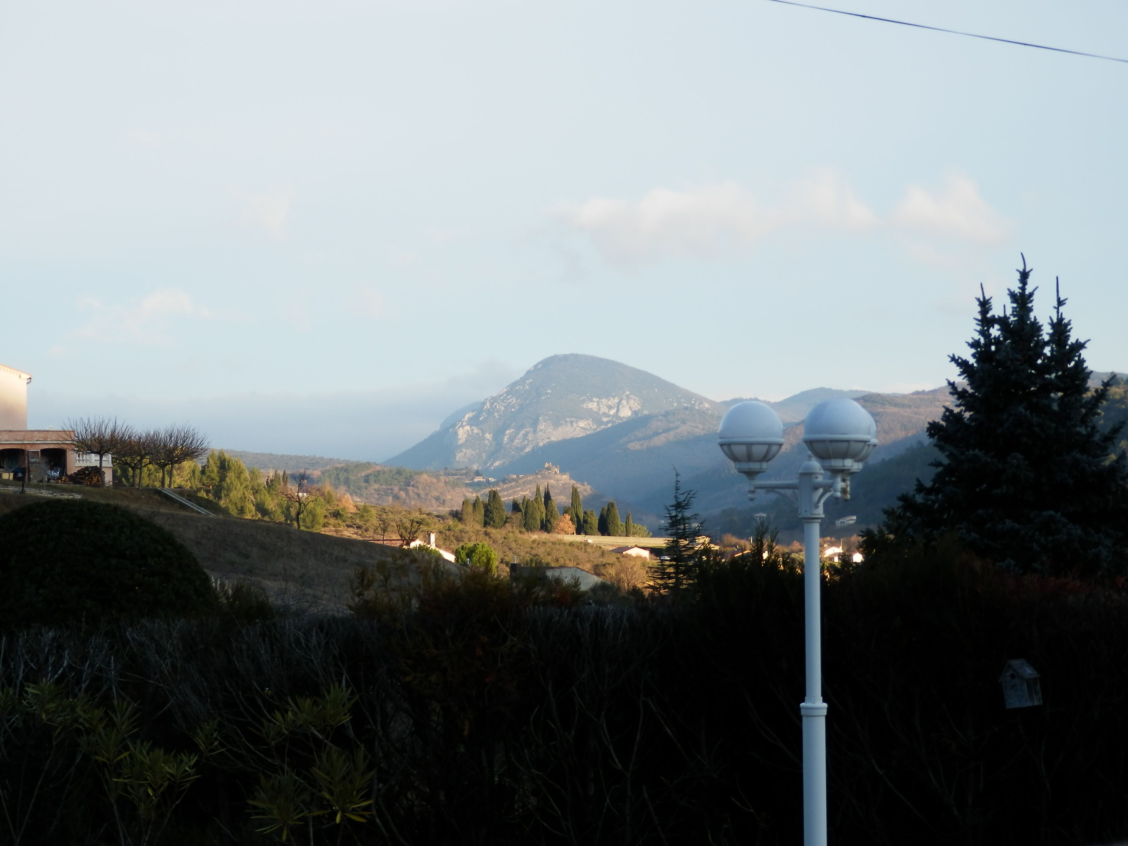 Un paysage montagneux avec un lampadaire et un bâtiment au premier plan.