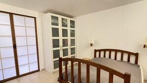 Un dormitorio con una cama de madera, un armario y un ventanal corredero.
