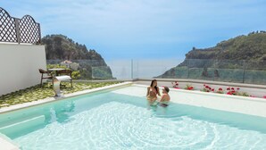 A pool with clear water, surrounded by a white wall and a view of cliffs. - Palazzo San Giovanni (Scala)